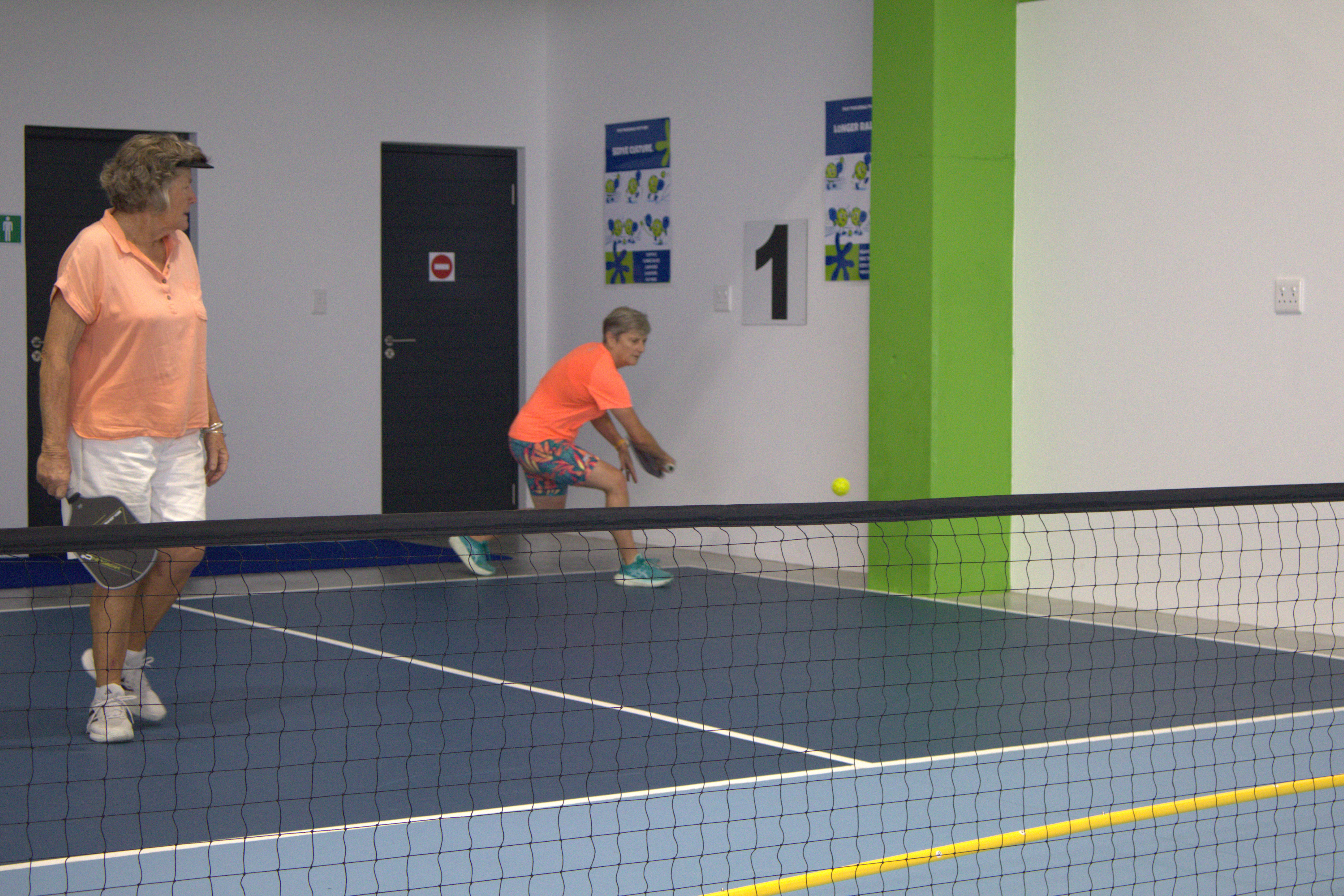Player digging out a low pickleball return at the kitchen line