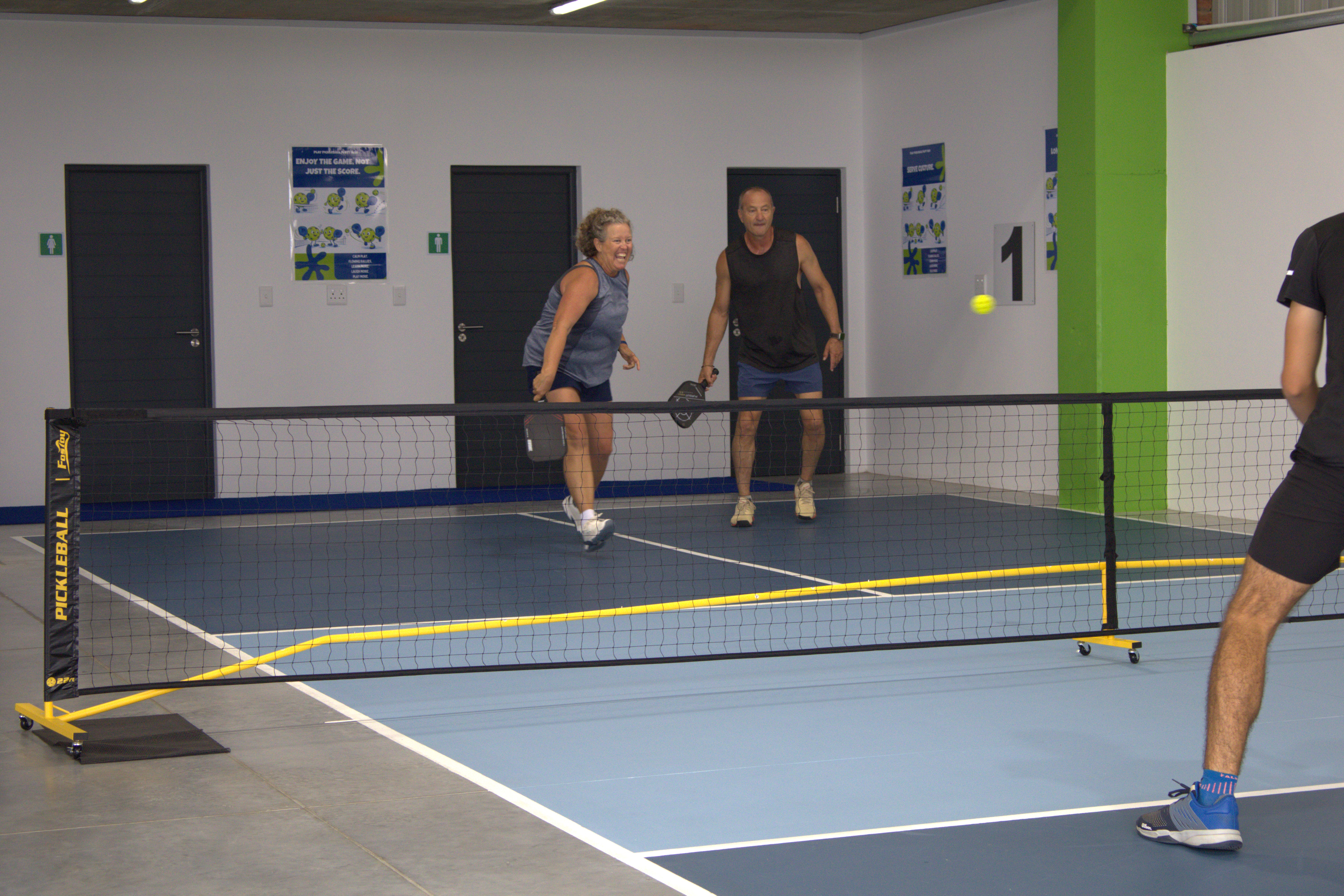 Four players enjoying a pickleball doubles match indoors